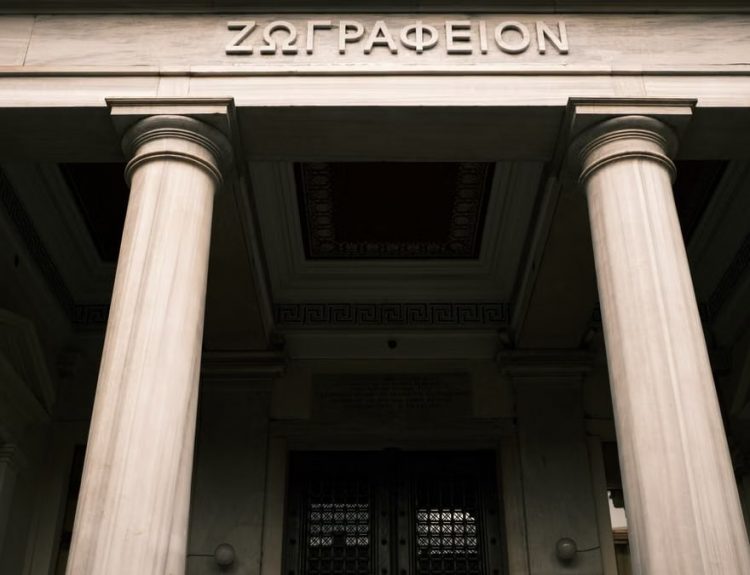 Low angle view of a historical building facade with Greek columns and inscriptions.