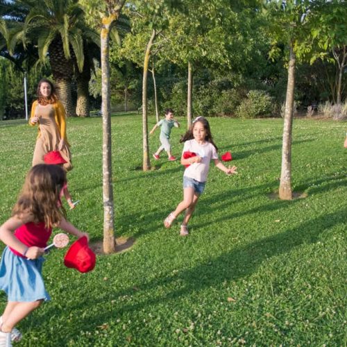 Kids and adults enjoy playing together in a lush, sunny park setting.
